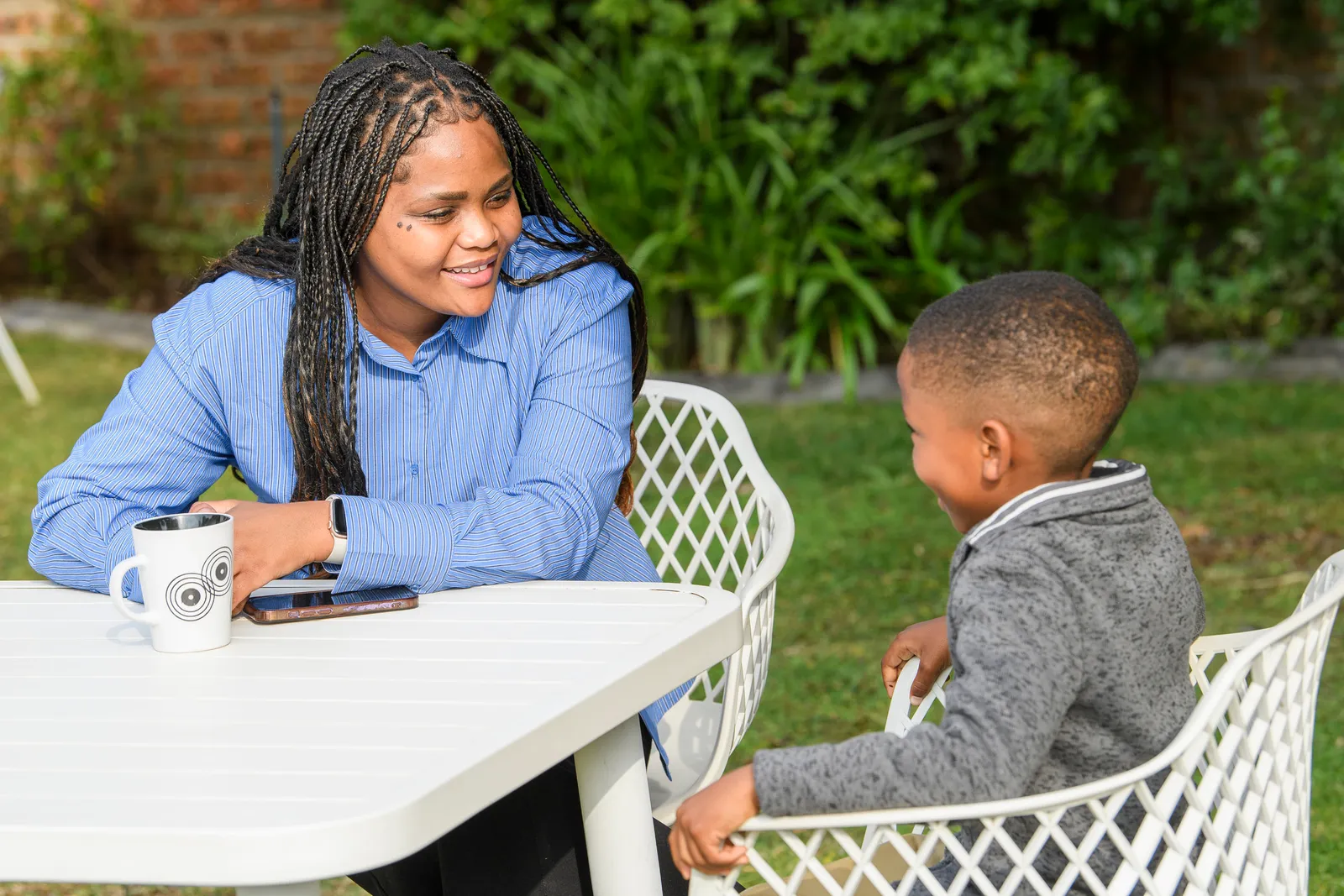 An Education Leader talking with a young learner across a garden table
