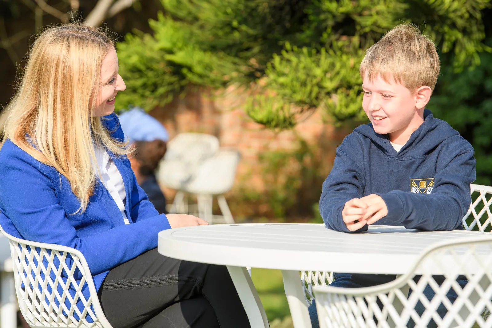 An Education Leader and student talking across a sunlit garden table