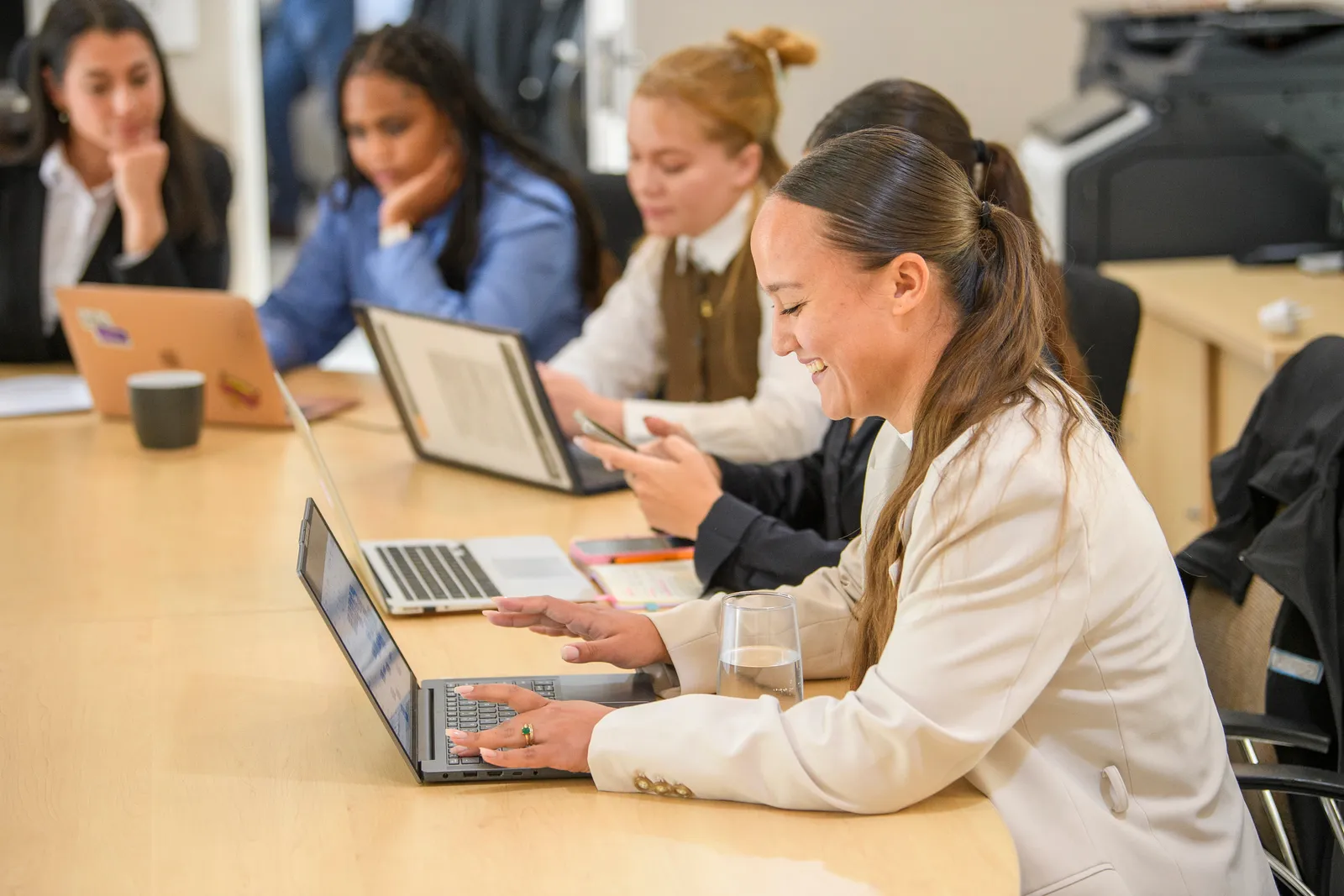 A Genius team member working at her laptop with colleagues