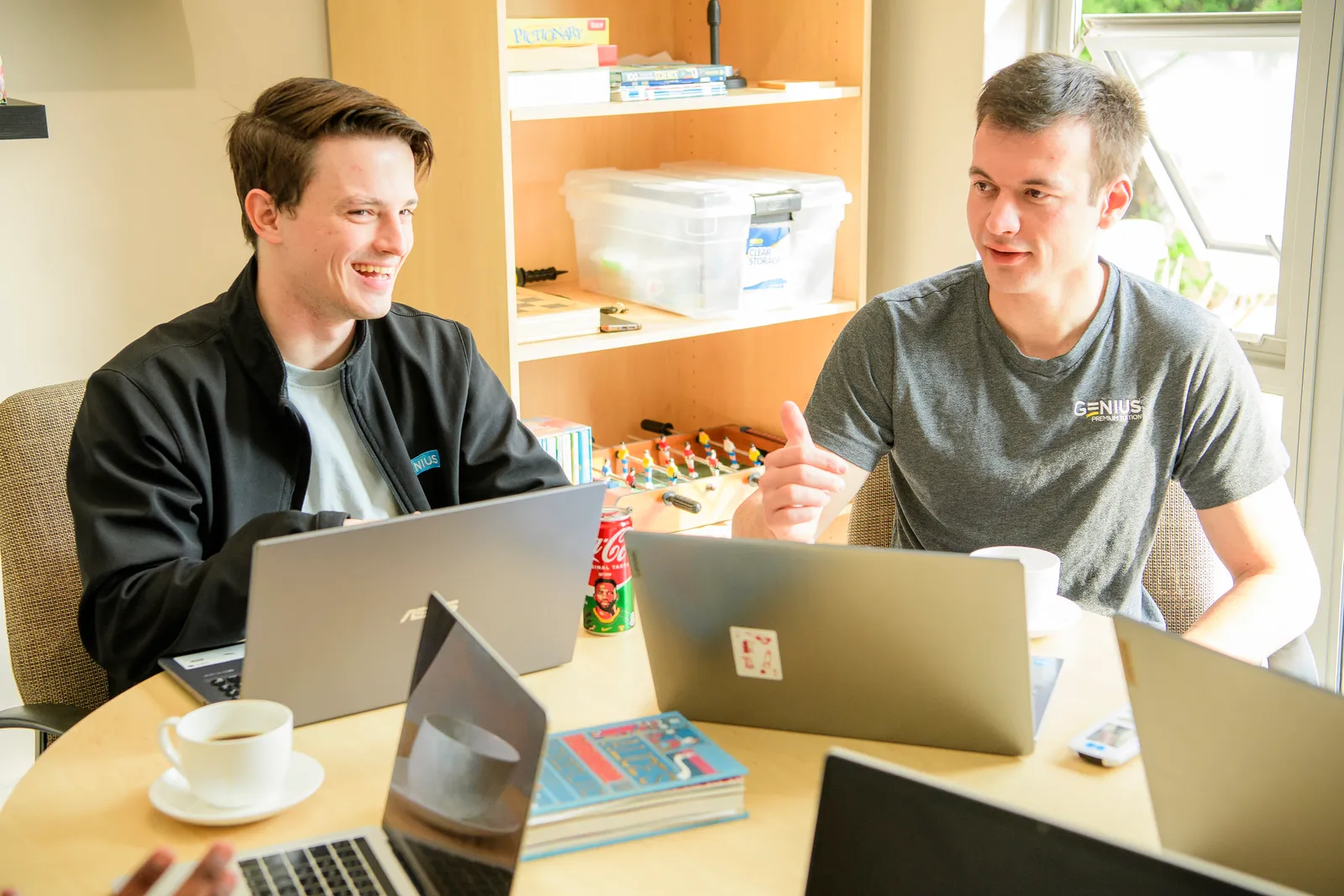 Genius colleagues collaborating across a table of laptops