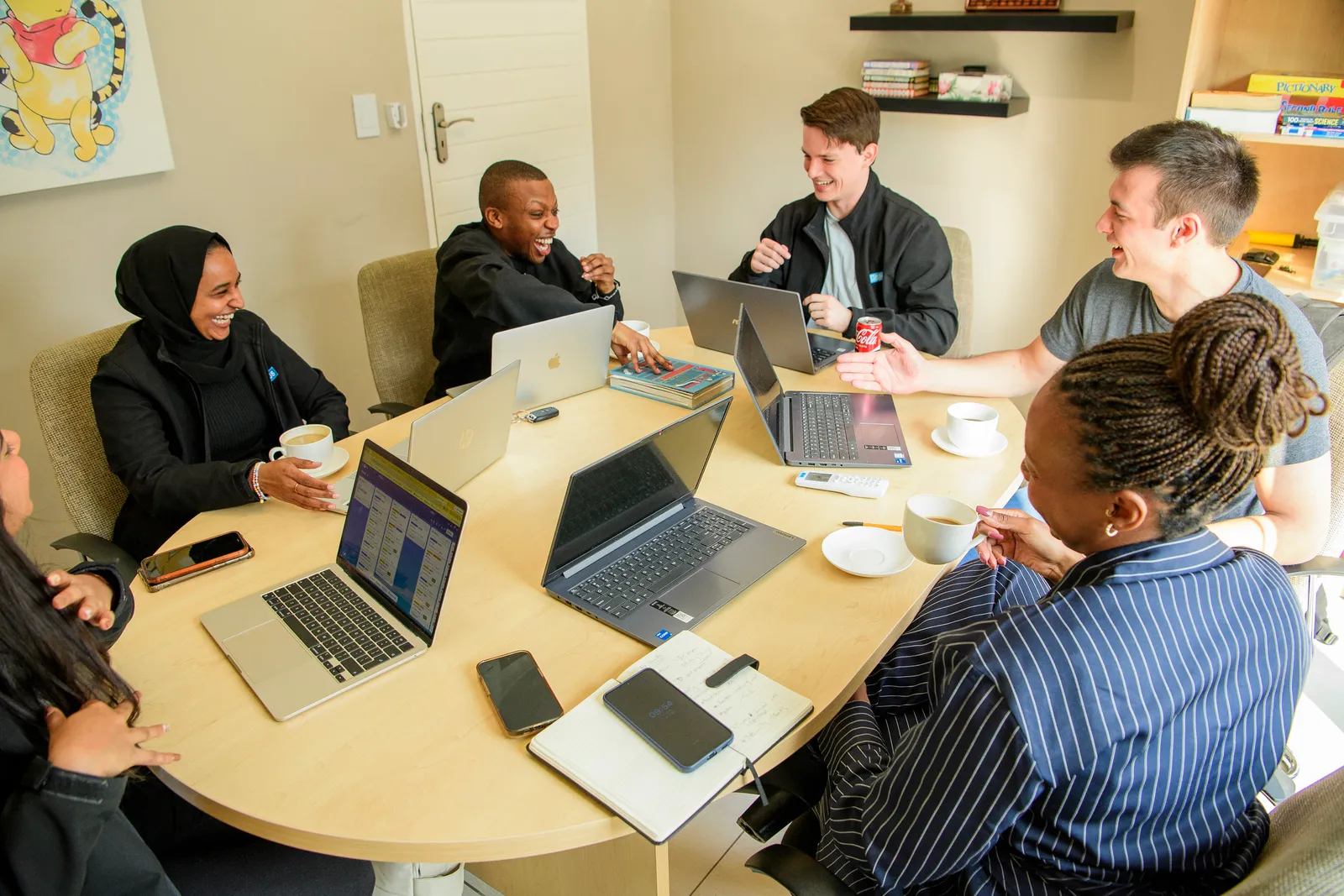 The Genius team working together around a table of laptops