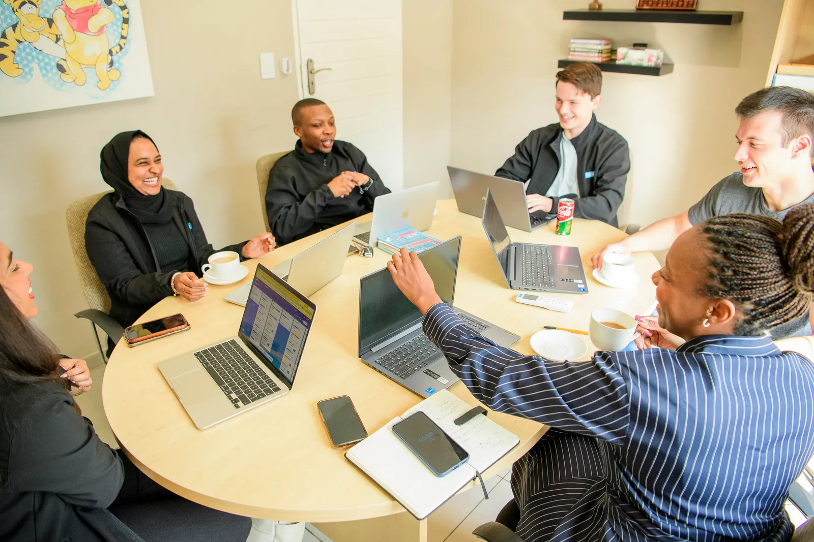 The Genius team laughing together around a working table