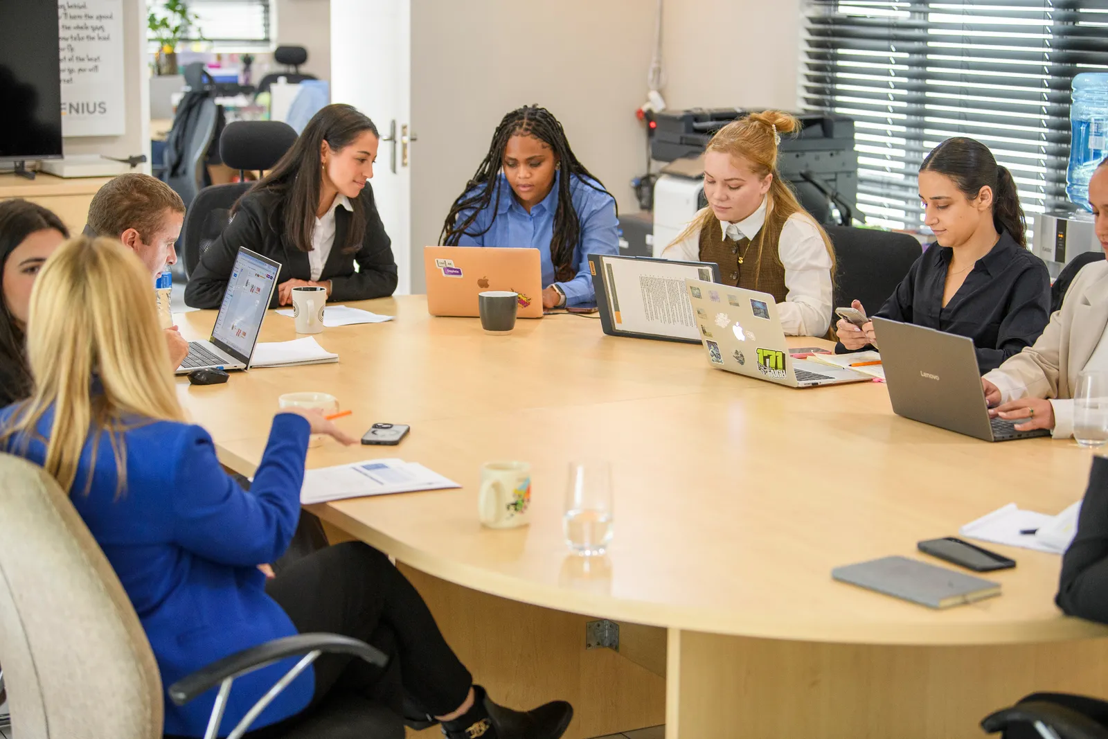 The Genius team collaborating around a table with laptops and notes