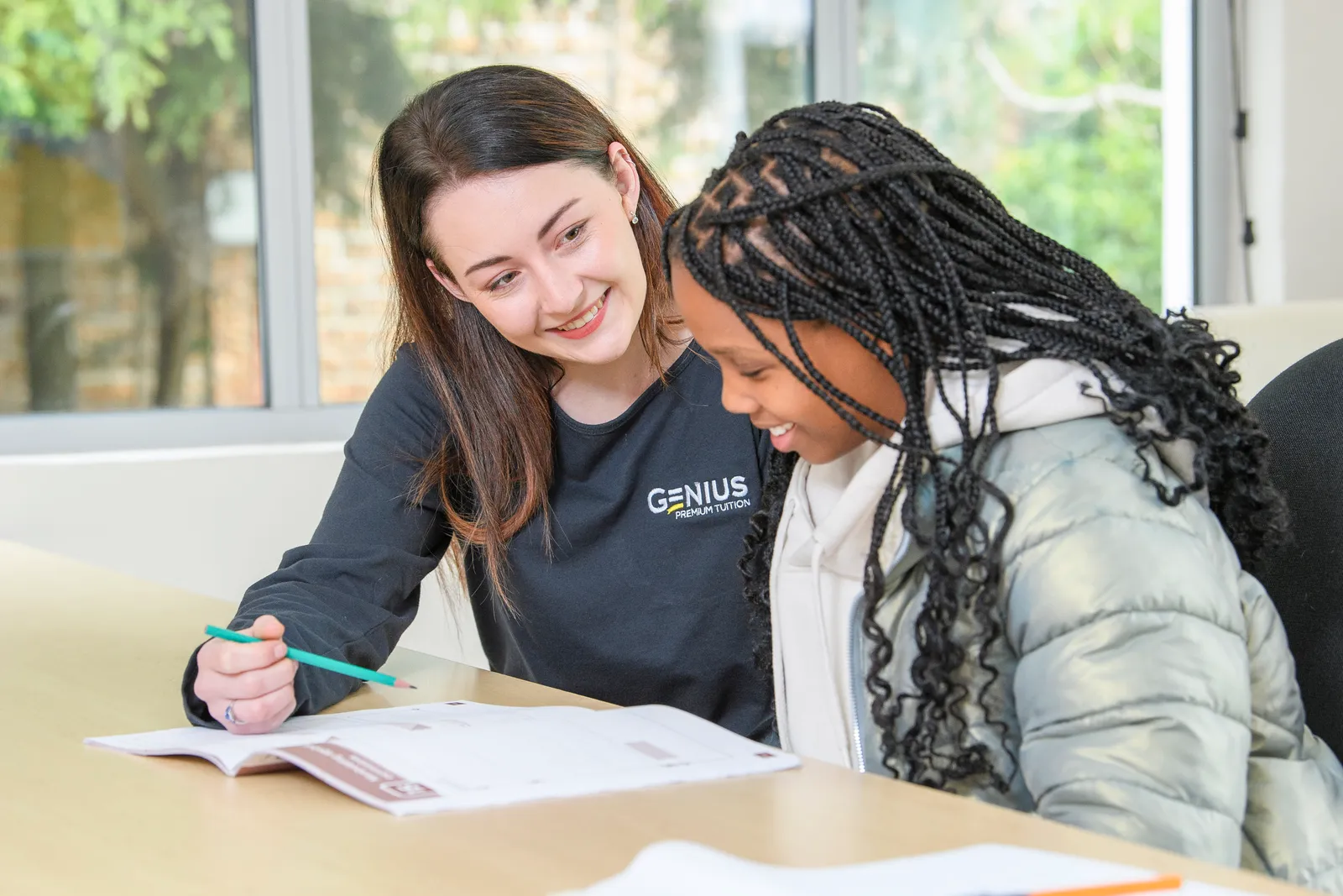 A Genius tutor and student working together over an open workbook