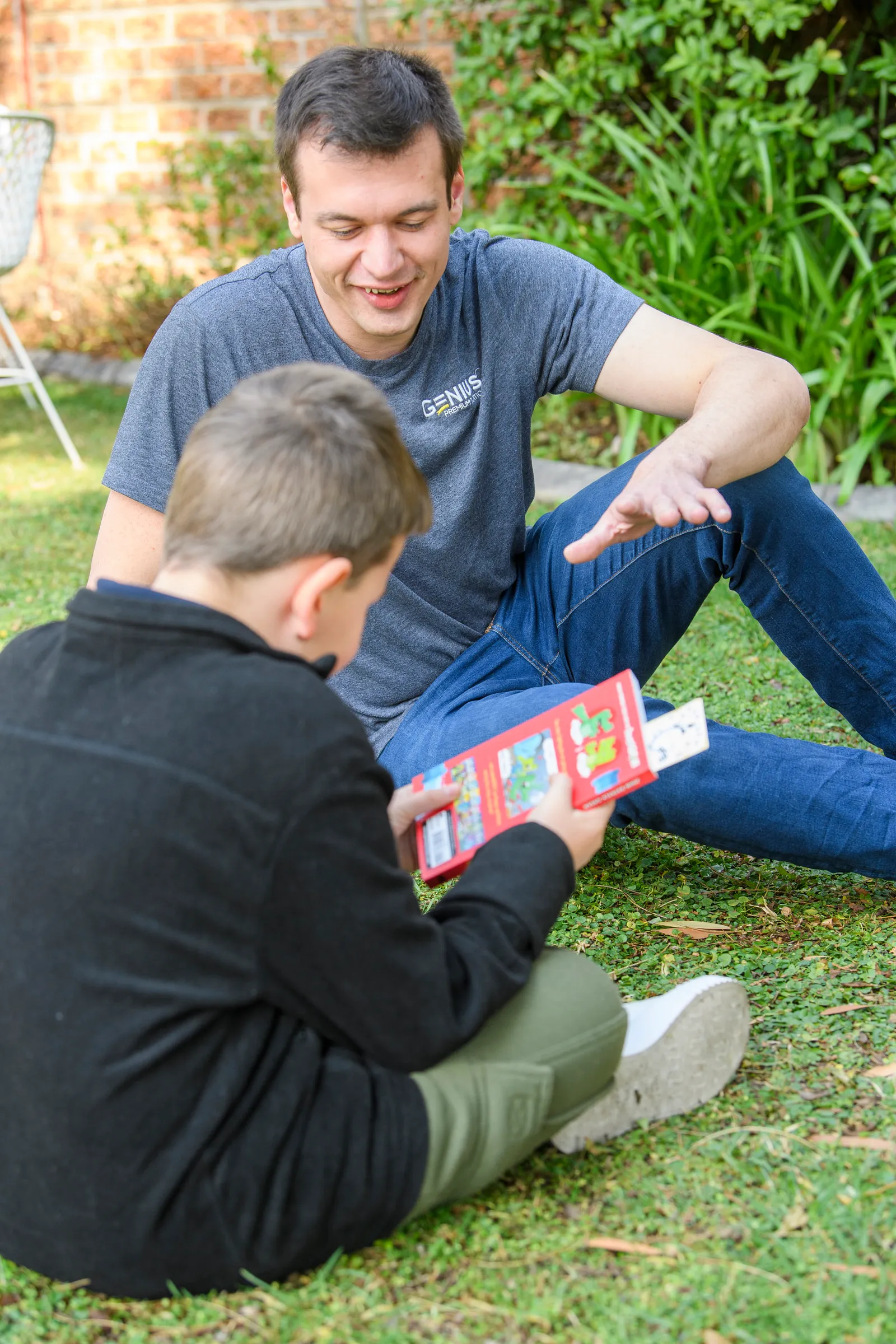 A Genius tutor supporting a young learner reading outdoors