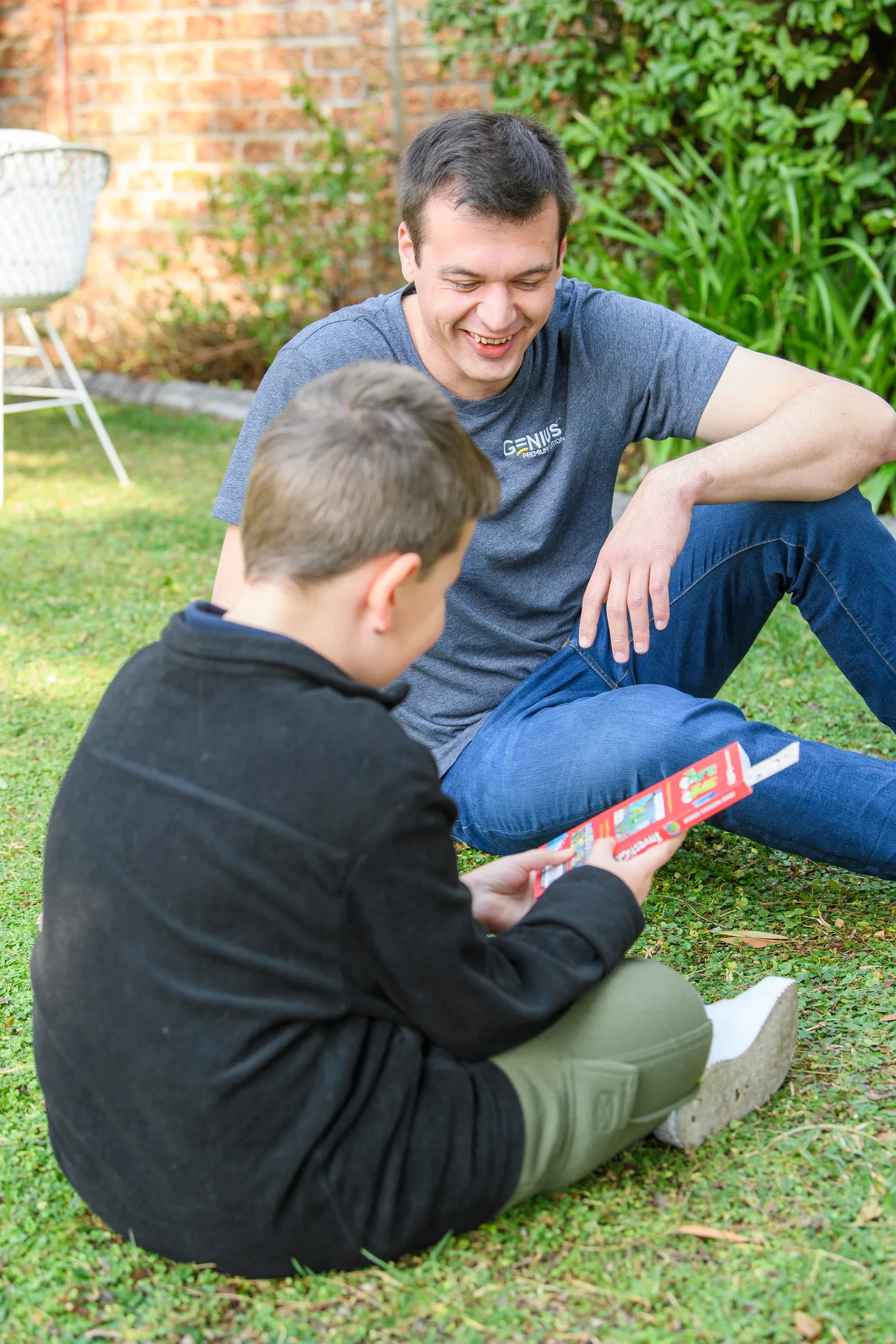 A Genius tutor and young learner laughing together over a book